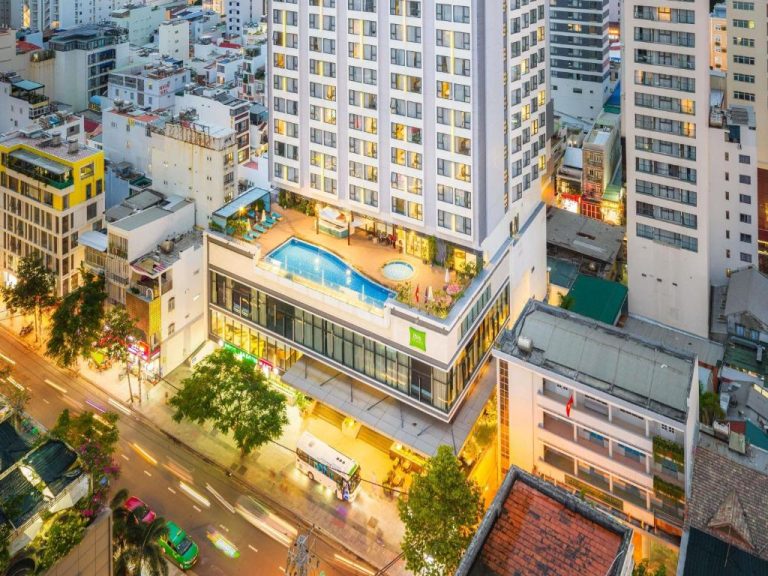 Vista aérea del ibis Styles Nha Trang con piscina en azotea e iluminación nocturna de la ciudad