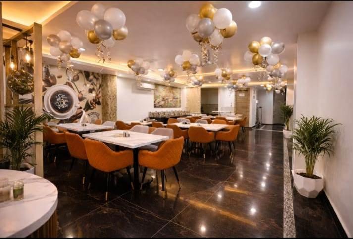Salón restaurante elegante con globos dorados y sillas naranjas en Hotel NS Plaza cerca del aeropuerto de Delhi
