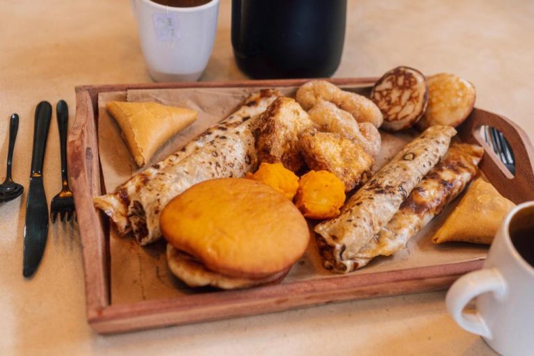 Bandeja de desayuno tradicional con crepes, samosas y bollería en el hotel Nyumbani Stonetown