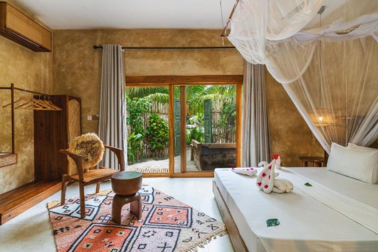 Habitación con cama dosel y mosquitera en Oke Ani Boutique Hotel con vistas al jardín tropical