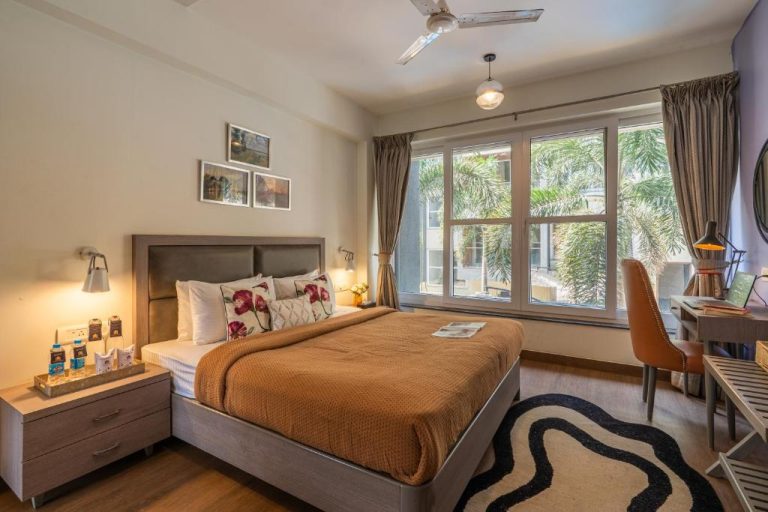 Habitación doble con cama queen, escritorio y ventanal con vistas verdes en Perfectstayz Premium Carnival Suites