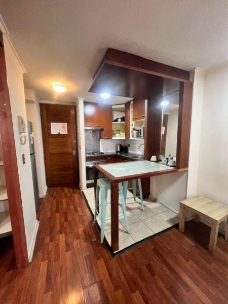 Cocina americana equipada con barra desayunador y taburetes en Dptos Merced Santiago