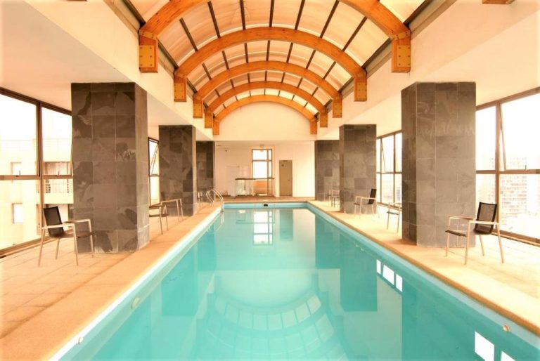 Piscina interior cubierta con techo de madera arqueado en Dptos Merced Santiago, Chile