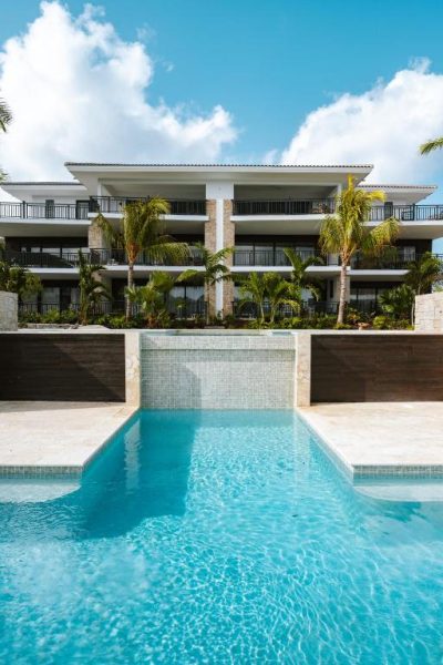 Piscina exterior con cascada del The Breeze en Blue Bay Curaçao Golf & Beach Resort rodeada de palmeras