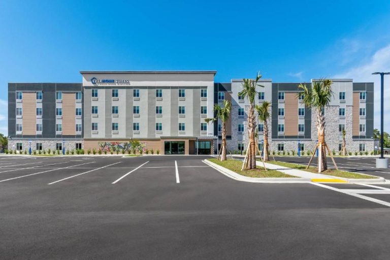 Fachada exterior y aparcamiento del Everhome Suites Panama City Beach con palmeras y cielo azul