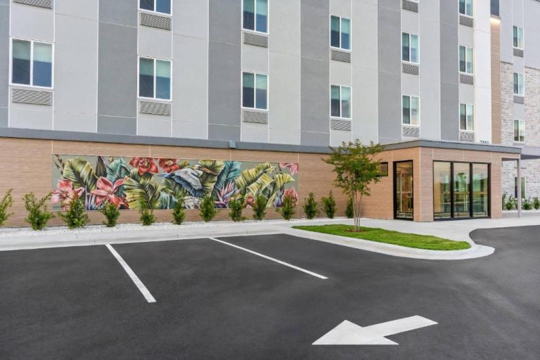 Fachada exterior con mural tropical del Everhome Suites Panama City Beach y aparcamiento
