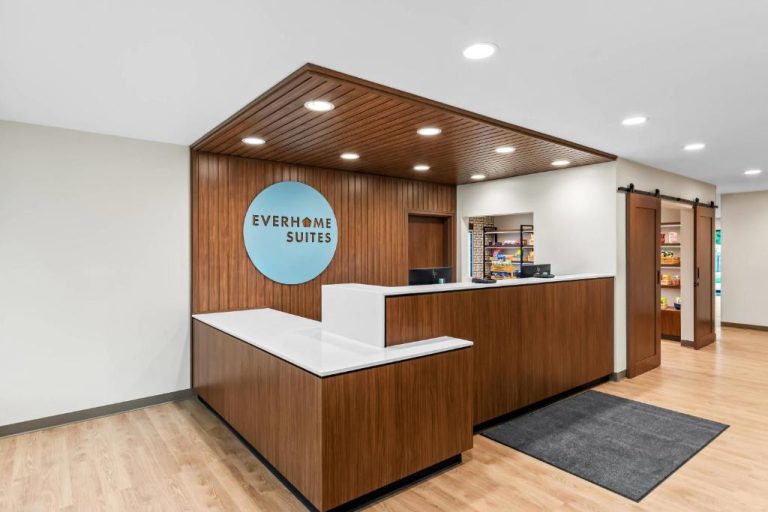 Recepción moderna de Everhome Suites Panama City Beach con mostrador de madera y logo del hotel