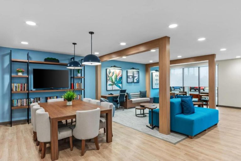 Sala común con comedor, sofá azul y TV del Everhome Suites Panama City Beach