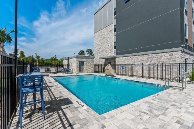 Piscina exterior con terraza y tumbonas azules del Everhome Suites Panama City Beach
