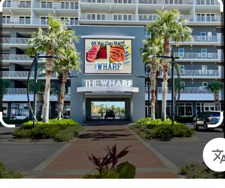 Entrada principal del resort Laketown Wharf con palmeras y cartel publicitario All You Can Yum