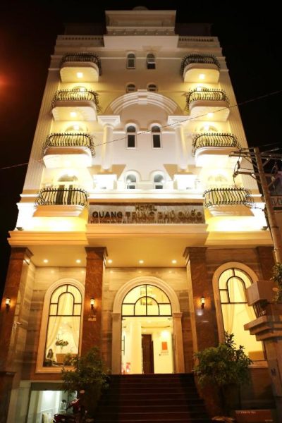 Fachada iluminada de noche del Quang Trung Phu Quoc Hotel con balcones y entrada principal