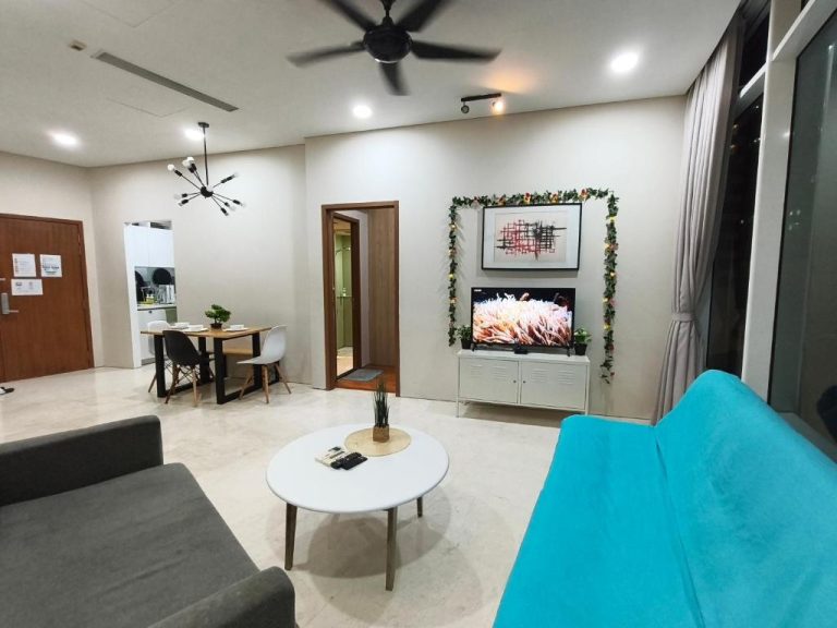 Salón moderno con sofá azul y televisor en Vortex Suites KLCC by Chia en Kuala Lumpur