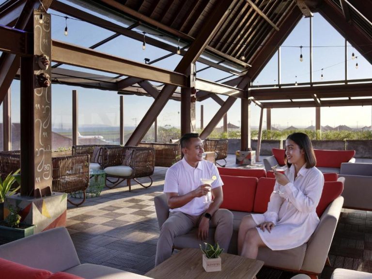 Pareja disfrutando de cócteles en la terraza lounge bar del Novotel Bali Ngurah Rai Airport