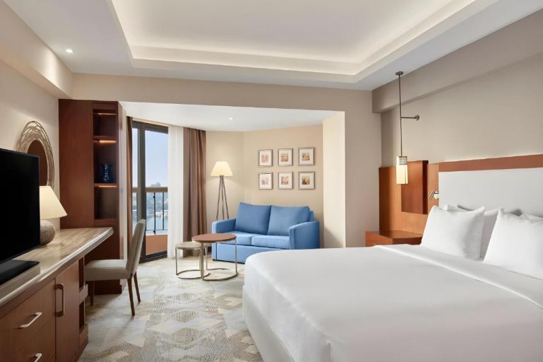 Habitación deluxe con cama king y sofá azul en Garden Hotel El Tahrir Downtown Cairo