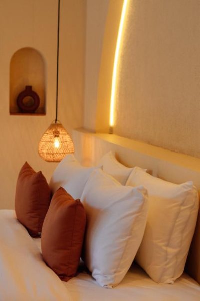 Habitación con cabecero iluminado y cojines en tonos tierra del Miliyana Boutique Hotel Adults Only