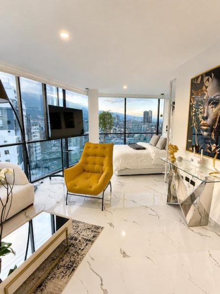 Suite de lujo con vista panorámica a la ciudad en NIDO Boutique Hotel, piso de mármol y silla amarilla