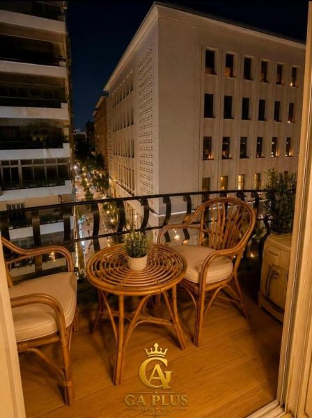 Terraza con sillas de ratán y vistas nocturnas a la ciudad en GA Plus Hotel Cairo Downtown