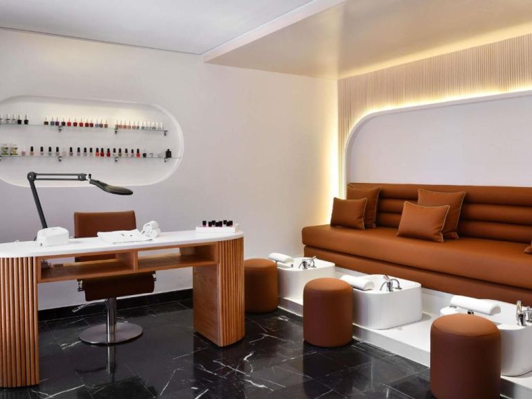 Sala de manicura y pedicura de lujo con sofá marrón y foot spa en Mövenpick Mansour Eddahbi Marrakech