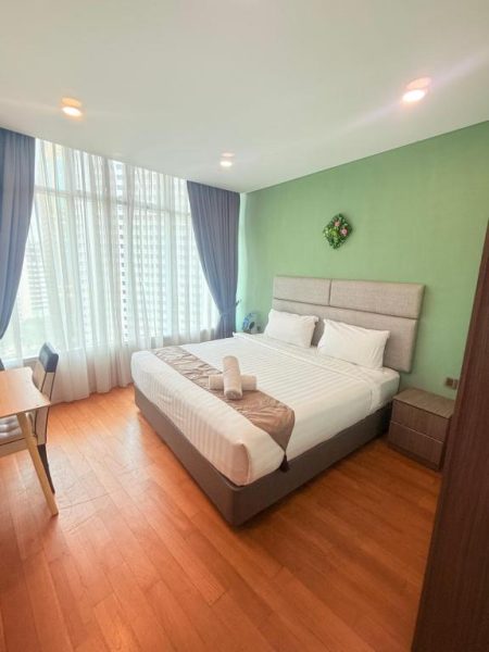 Habitación doble con cama king size, suelo de parquet y pared verde en el hotel Klcc Vortex