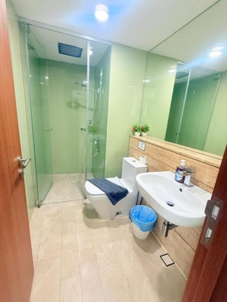 Baño moderno con ducha de cristal, lavabo y paredes verdes en el hotel KLCC Vortex