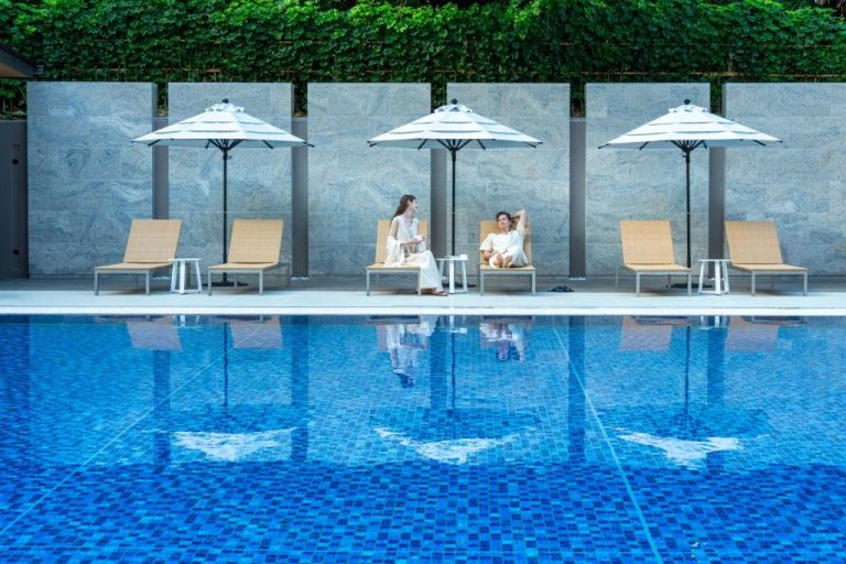 Piscina exterior con tumbonas y sombrillas blancas del Okinawa Harborview Hotel