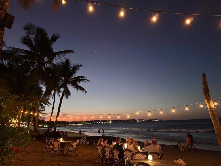 Cena romántica en la playa con guirnaldas de luces al atardecer en La Curadiña Encuentro Surf Hotel