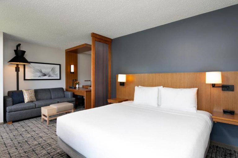 Habitación king con sofá y escritorio en el Hyatt Place Manatí, decoración moderna en tonos grises y madera