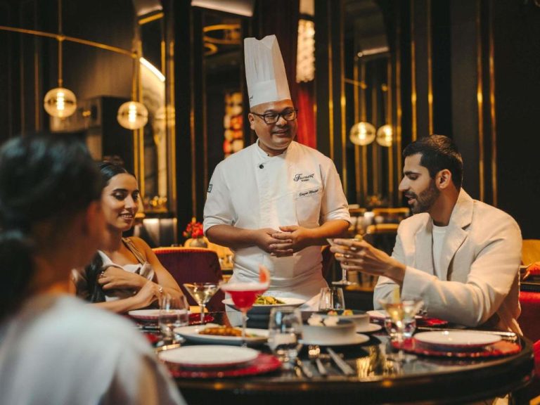 Chef del Fairmont Mumbai presentando platos de alta cocina a comensales en el restaurante gourmet del hotel