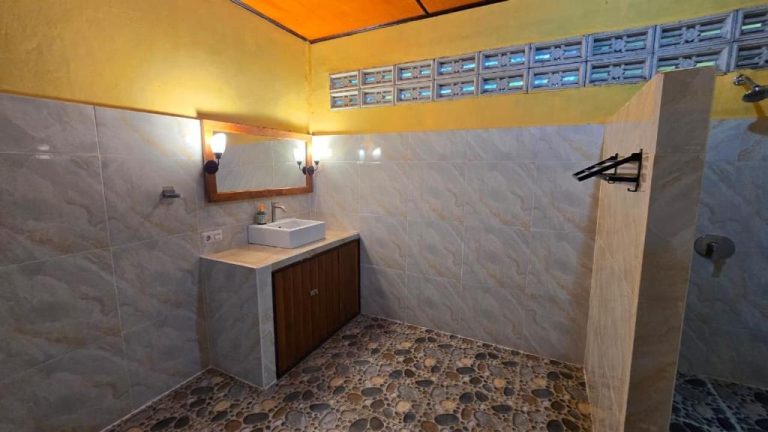 Baño moderno con lavabo, espejo y ducha de piedra natural en Tangkoko Sanctuary Villa