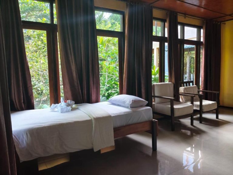 Habitación doble con vistas al jardín tropical en Tangkoko Sanctuary Villa, con camas individuales y sillones