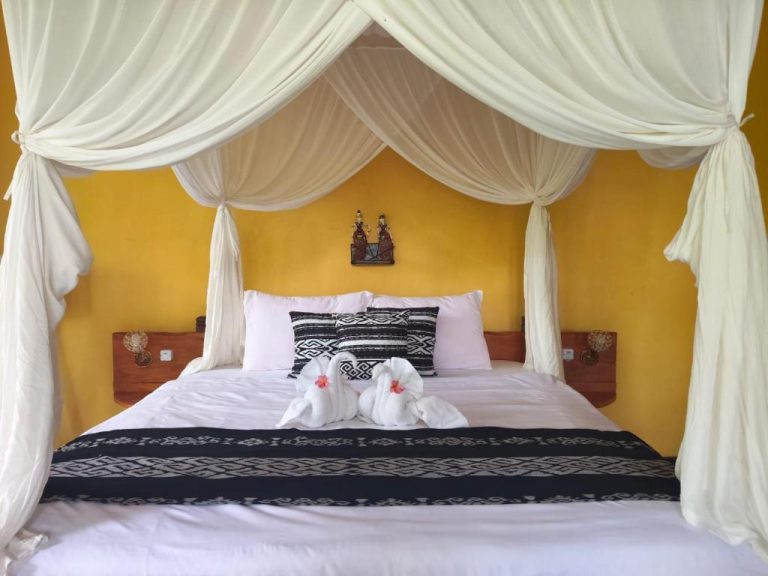 Habitación con cama dosel y cortinas blancas en Tangkoko Sanctuary Villa con decoración balinesa