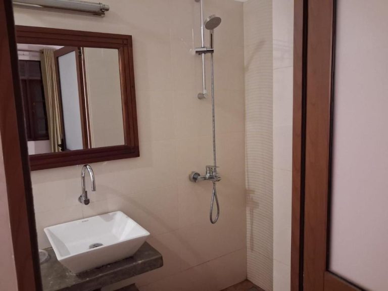 Baño moderno con ducha, lavabo blanco y espejo con marco de madera en River Tree Bolgoda