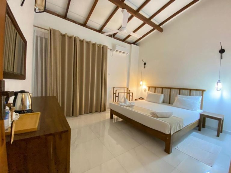 Habitación doble con cama de madera, ventilador de techo y aire acondicionado en River Tree Bolgoda