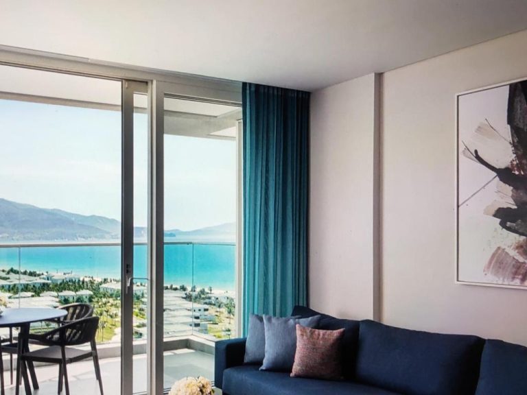 Salón con sofá azul y vistas panorámicas al mar y playa en The Manito Seaview Suites