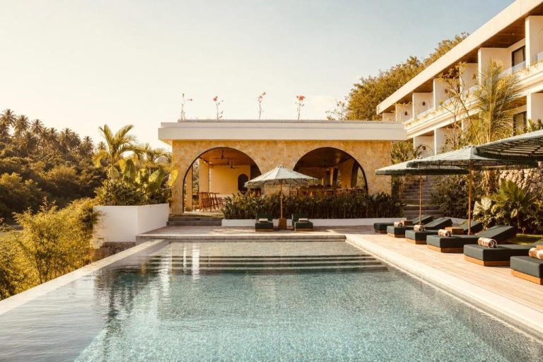 Piscina infinita con tumbonas y zona de relax del Kanalla Boutique Hotel rodeada de vegetación tropical