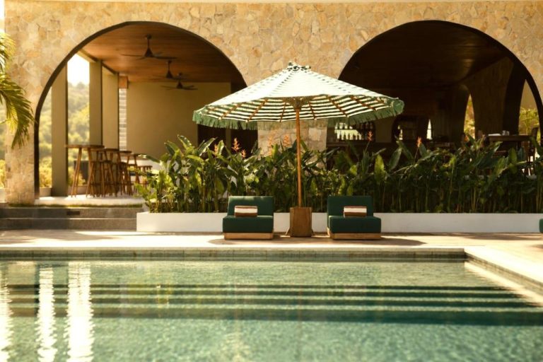 Piscina exterior con tumbonas y sombrilla del Kanalla Boutique Hotel rodeada de vegetación tropical
