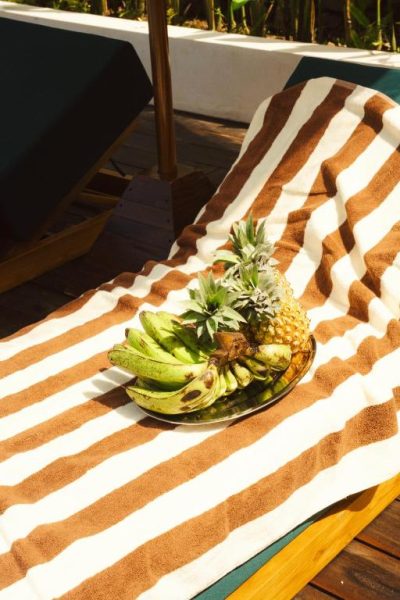 Bandeja de frutas tropicales con piña y plátanos en tumbona junto a la piscina del Kanalla Boutique Hotel