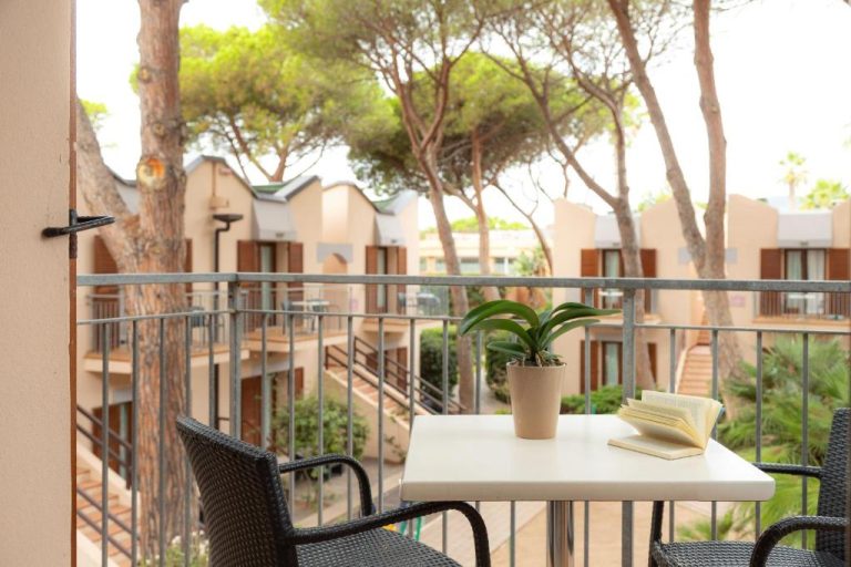 Terraza privada con mesa y sillas del Hotel Corte Rosada Adults Only, rodeada de pinos y jardines