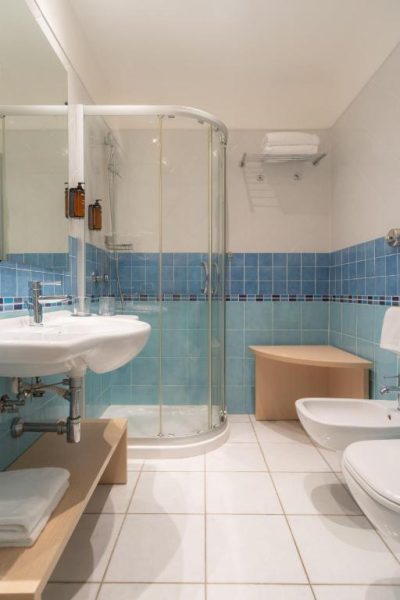 Baño moderno con ducha de cristal y azulejos azules en Hotel Corte Rosada Adults Only by Meliá