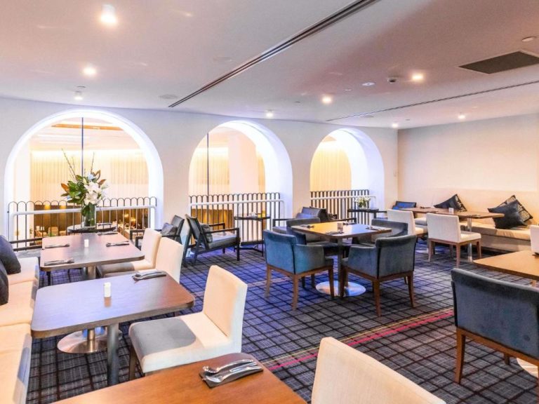 Elegante restaurante del Swissotel Sydney con mesas dispuestas y arcos decorativos blancos iluminados