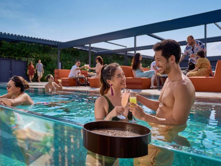 Pareja disfrutando de cócteles en la piscina rooftop del Pullman Singapore Hill Street