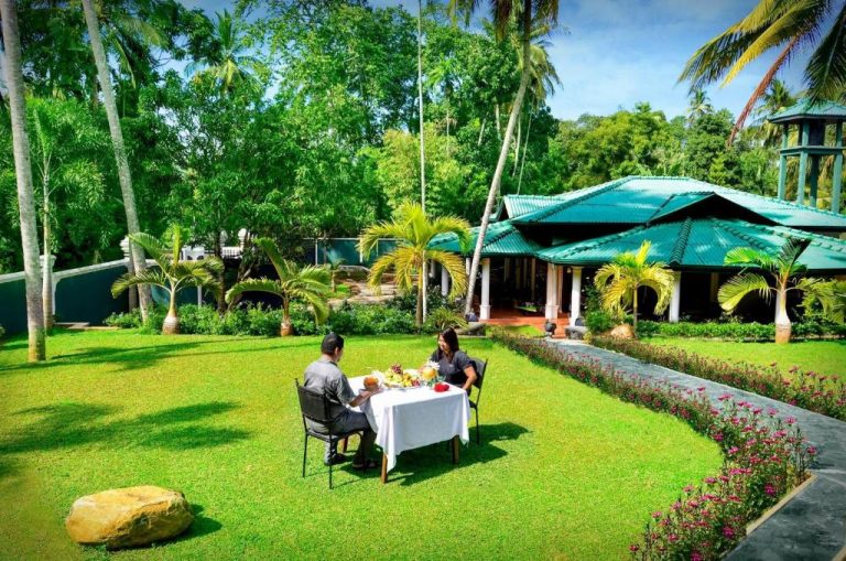Pareja disfrutando de una cena romántica al aire libre en el jardín tropical de The Kings Villa