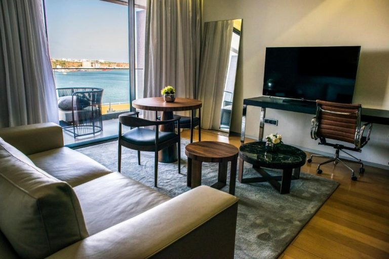 Salón elegante con sofá, mesa de comedor y vistas al mar desde la suite del Hotel Pérola