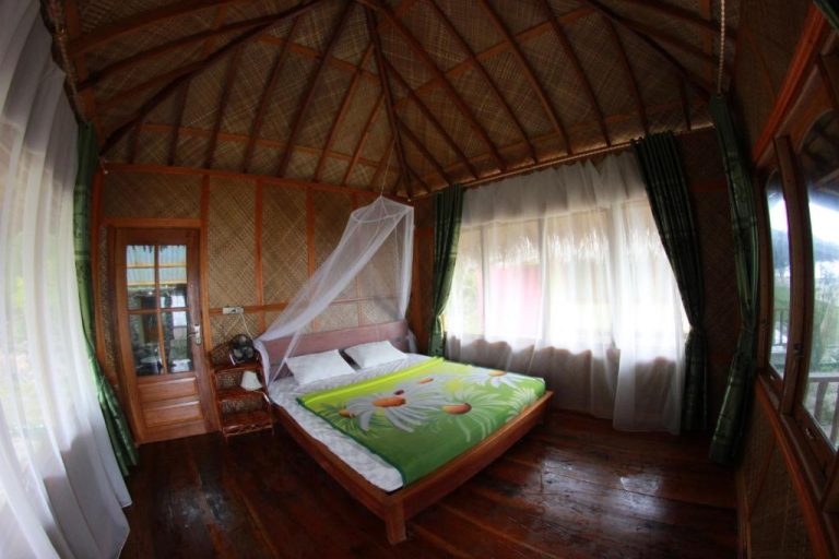 Habitación con cama doble, mosquitera y techo de paja en Ricky's Beach House