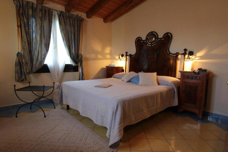 Habitación doble clásica con cabecero de madera tallada y vigas de madera en Hotel Su Lithu