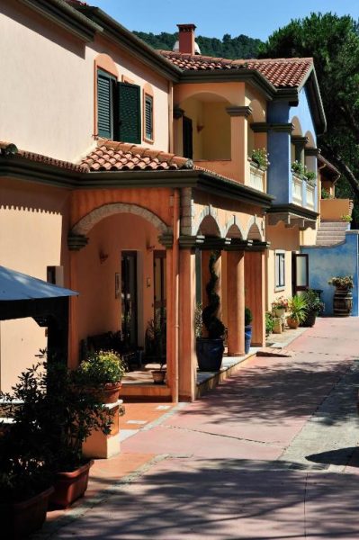 Fachada exterior con jardines y acceso principal del Hotel Su Lithu con arquitectura mediterránea