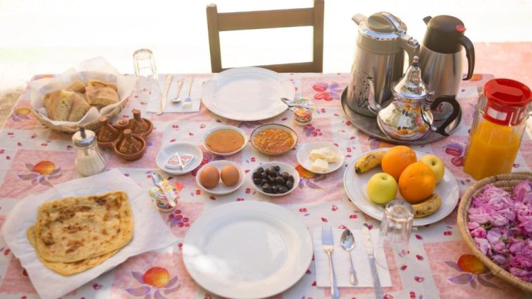 Desayuno marroquí tradicional con frutas, msemen, huevos y té en Kasbah Hotel Camping Jurassique
