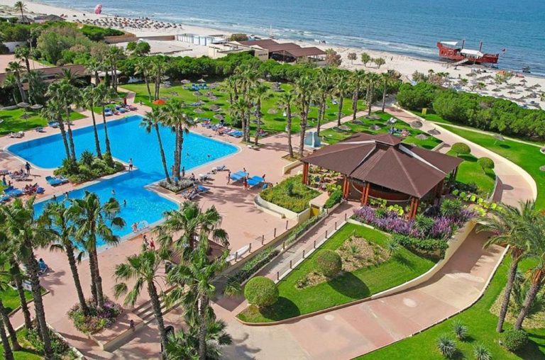 Vista aérea de las piscinas exteriores y jardines tropicales del Sahara Beach Aquapark Resort con acceso directo a la playa