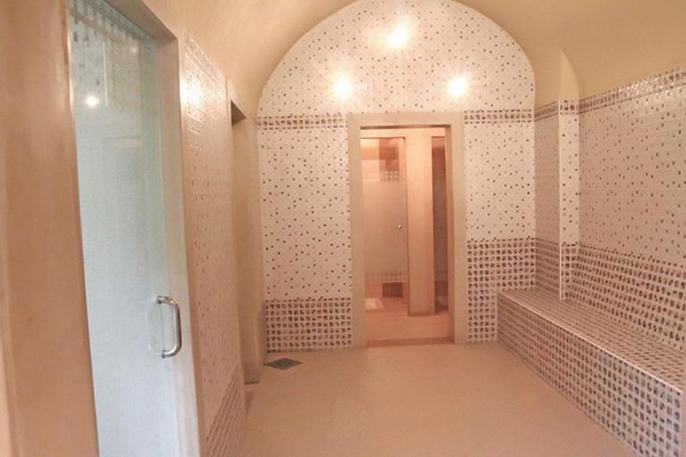 Baño turco hammam con mosaicos y arco de piedra en el spa del Sahara Beach Aquapark Resort