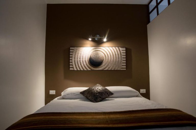 Habitación doble de estilo zen con cama matrimonial y pared marrón en Hotel Casa Ecuatreasures Centro Historico